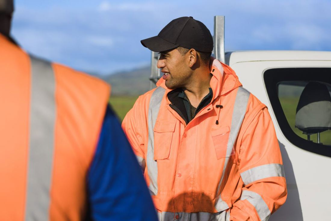 Dairy farm workers in high visibility clothing discussing farm issues out in the field