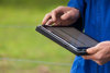 A close up of a dairy farmer in overalls holding an iPad.