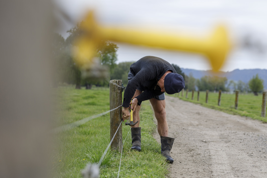 Man using a hammer to work on a fence