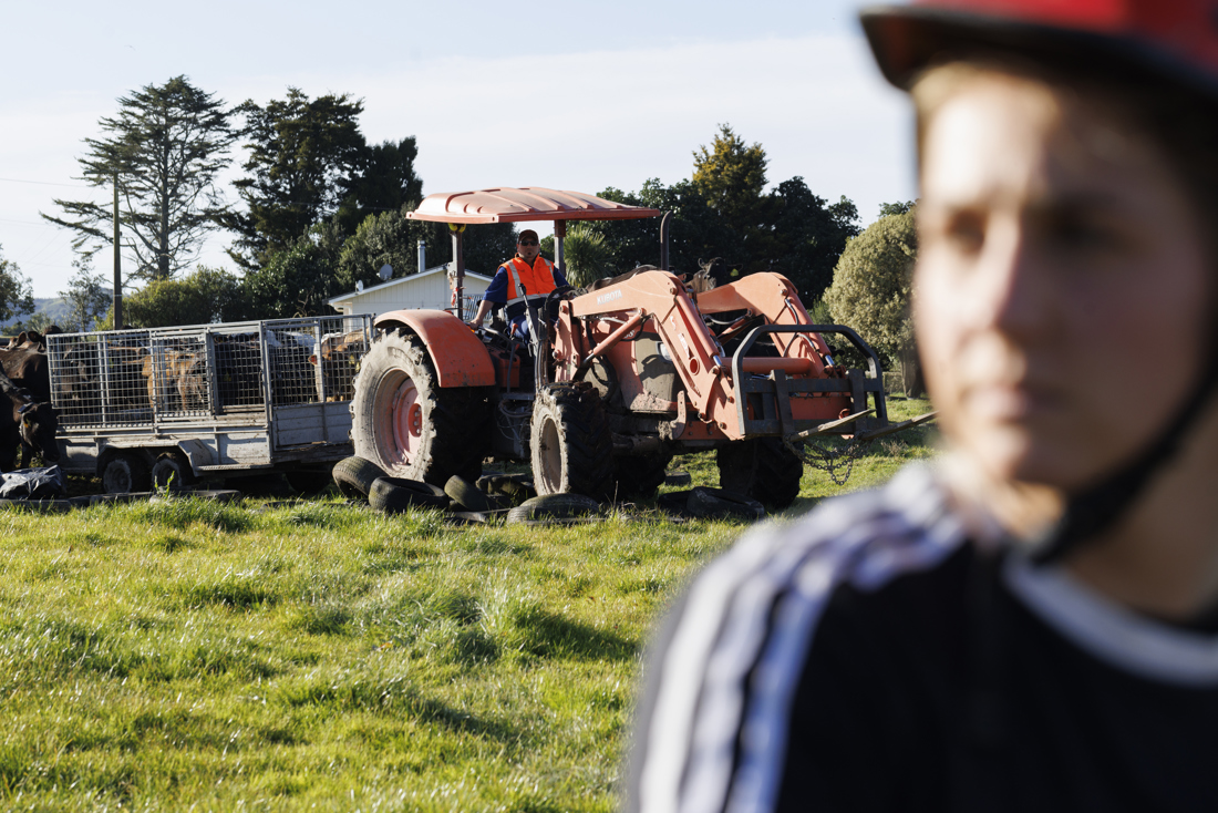 A farmer riding along a red tractor with a nearby individual