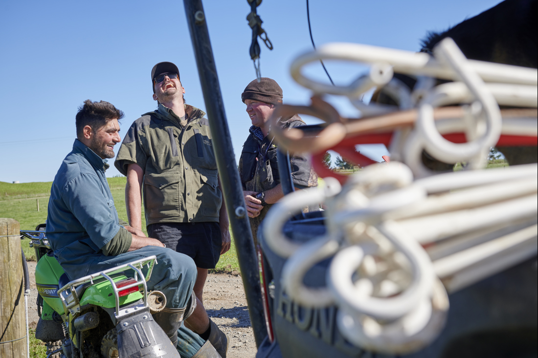 A group of happy men standing next to a tractor