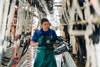 A female farm worker milking cows in a herringbone dairy