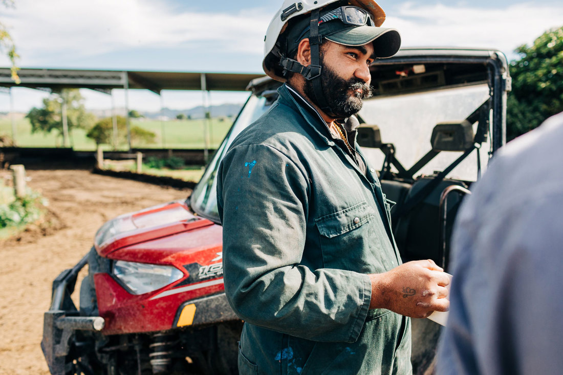 Farm workers stopped on a farm track talking with a farm vehicle in the background