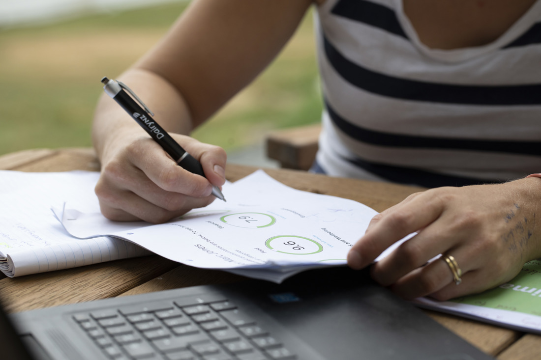 A woman holding a pen and papers with numbers on it
