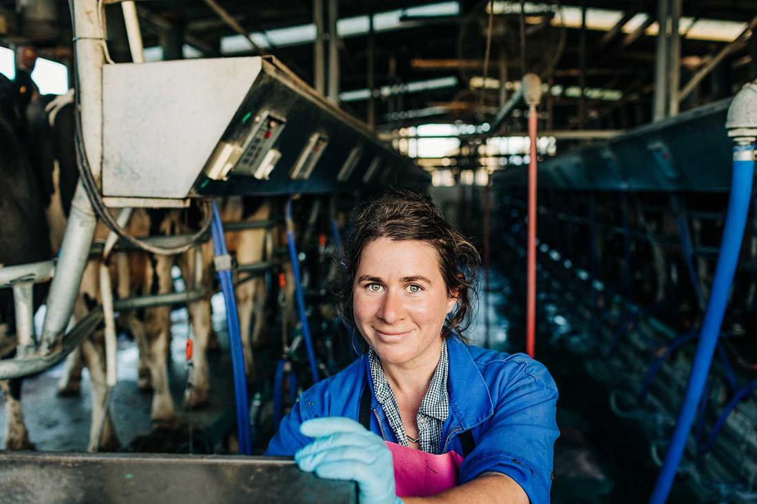 A female dairy farmer operating machinery in the farm dairy