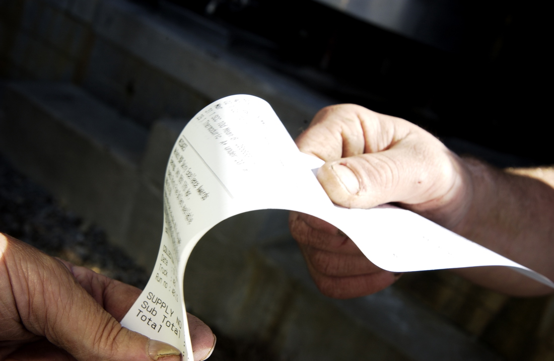 Close up focus of individuals checking on an invoice slip regarding purchase details