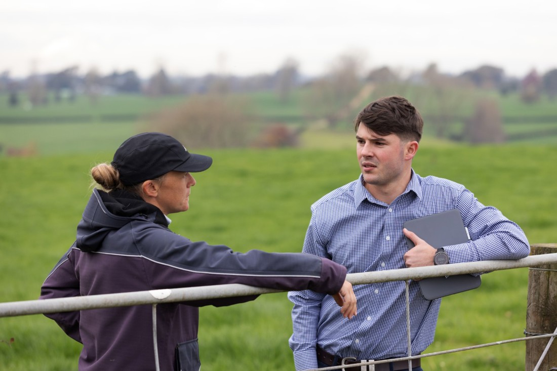 A business advisor talking to a dairy farmer out in a paddock